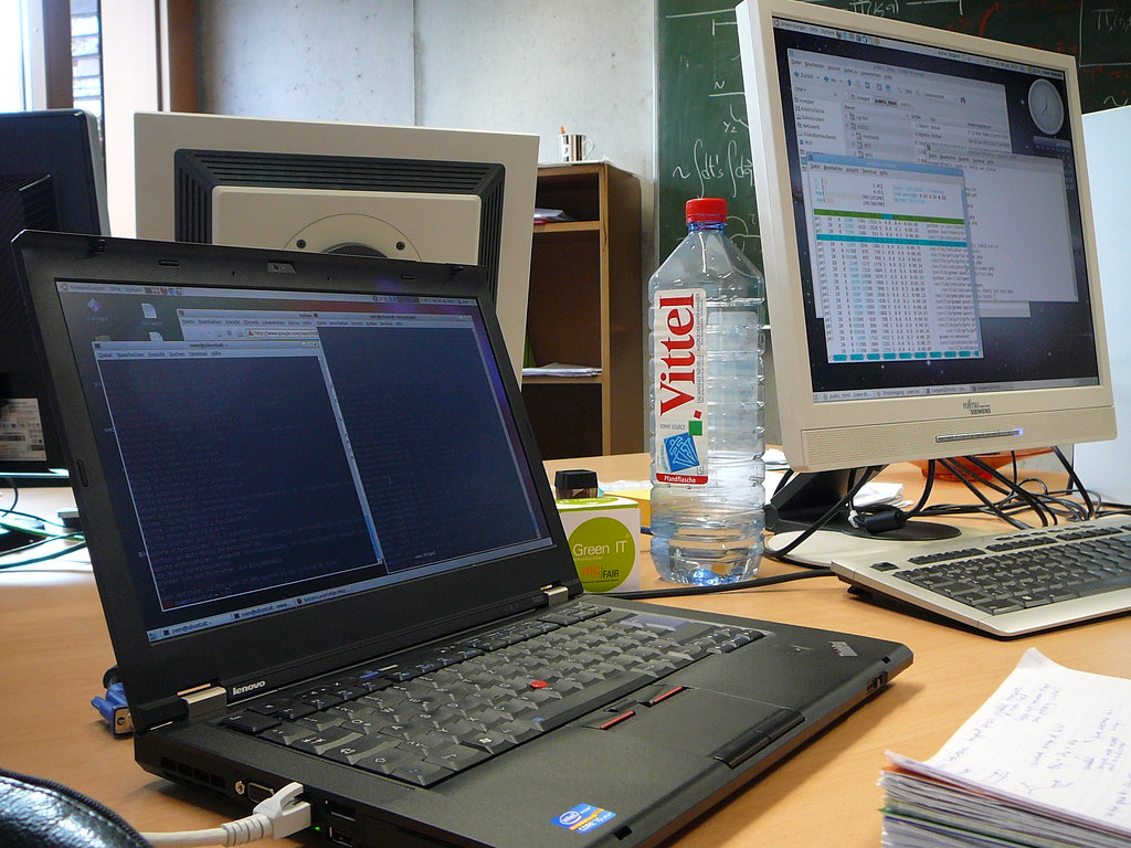 Desk setup for website form QA with laptop, external monitor, and handwritten test notes.